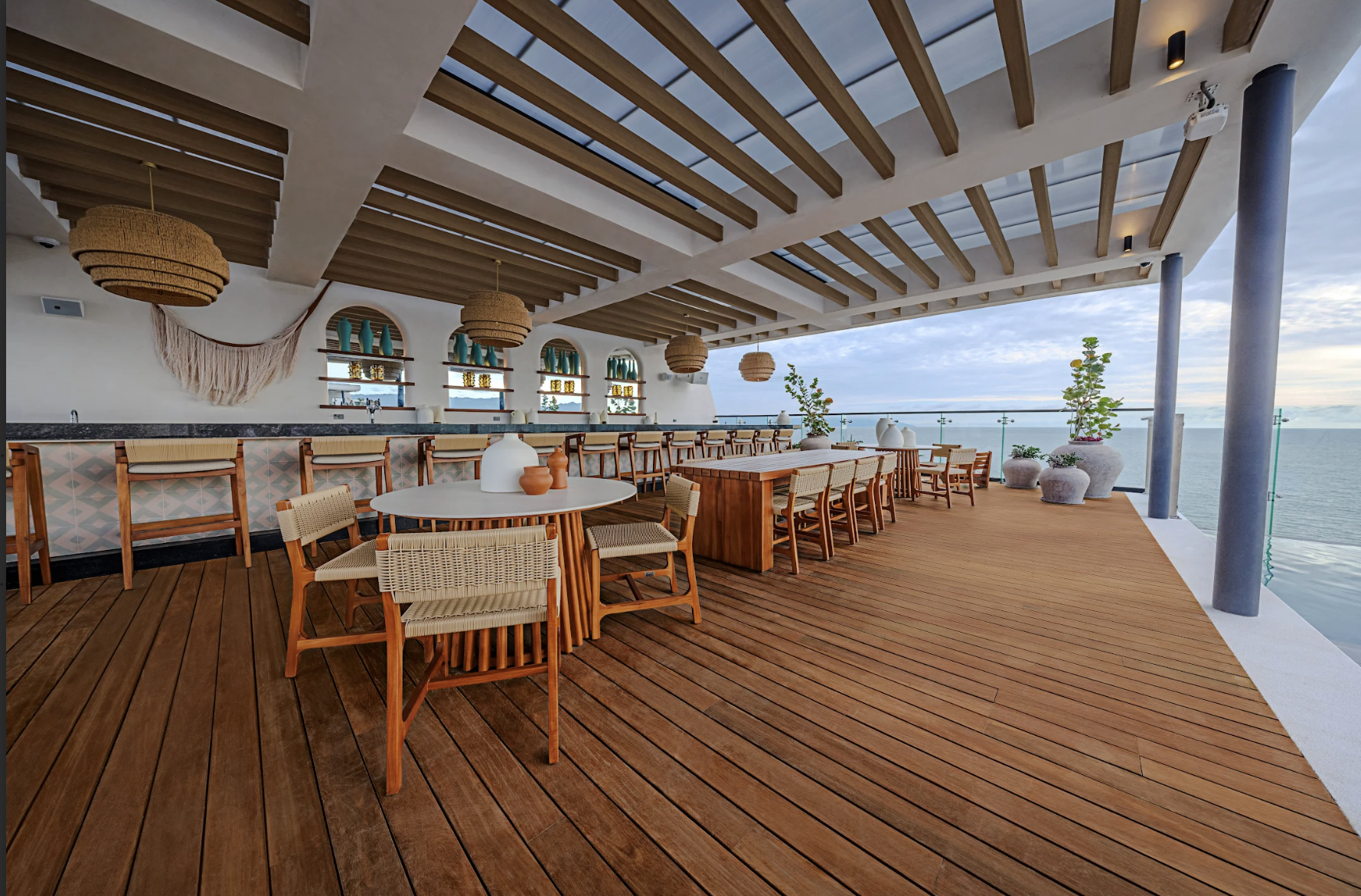altorooftop3 be all inclusive Open-air seaside restaurant deck with wooden floor, wicker chairs, and round tables overlooking the ocean.