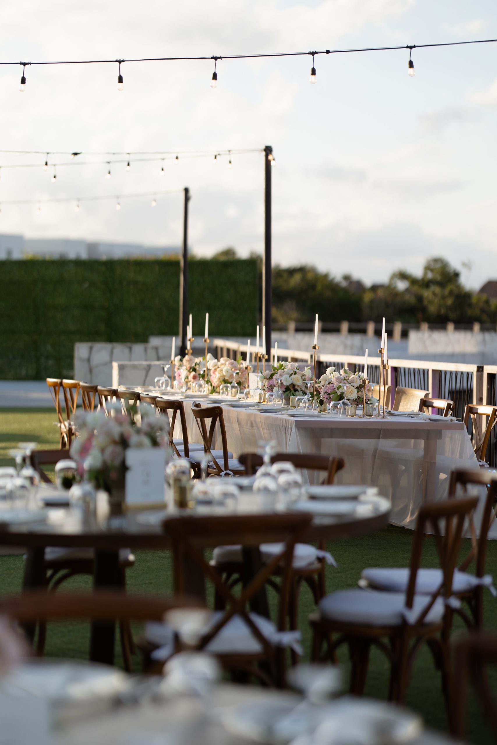 brandon olivia be all inclusive Outdoor wedding reception setup with long tables, floral centerpieces, and string lights overhead