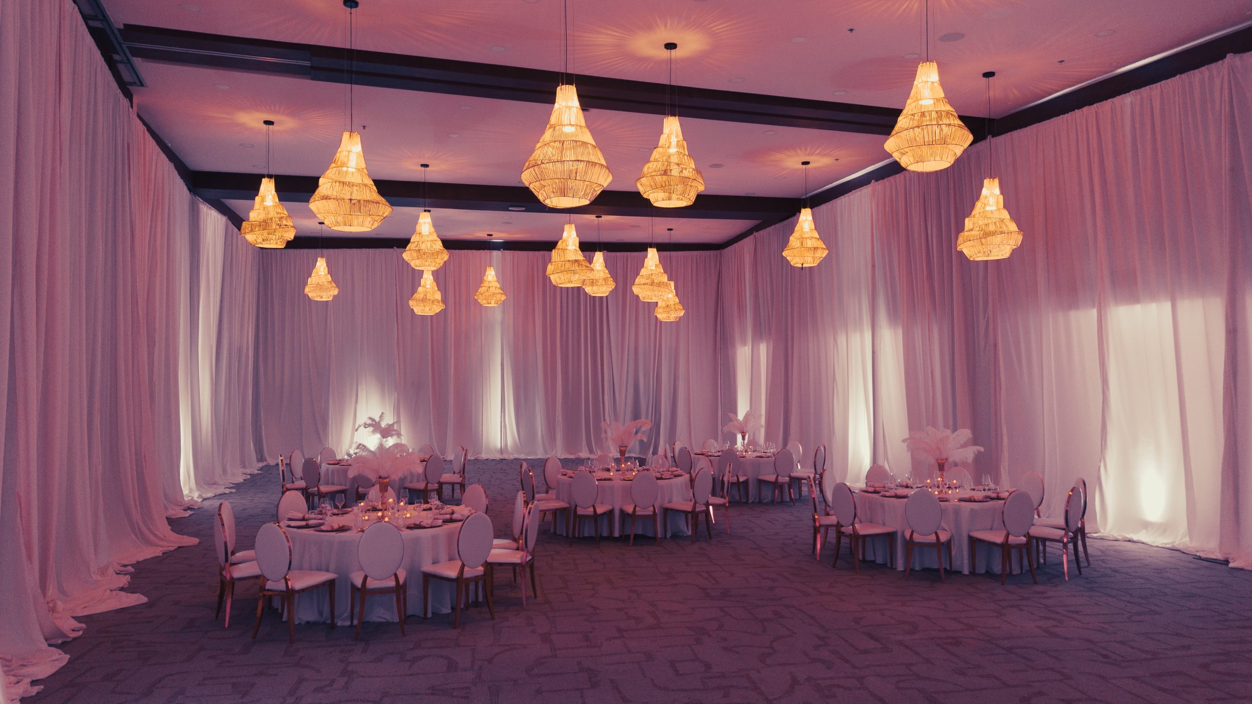 dji0982 be all inclusive Banquet hall with pink lighting, chandeliers, and round tables set for a formal event.