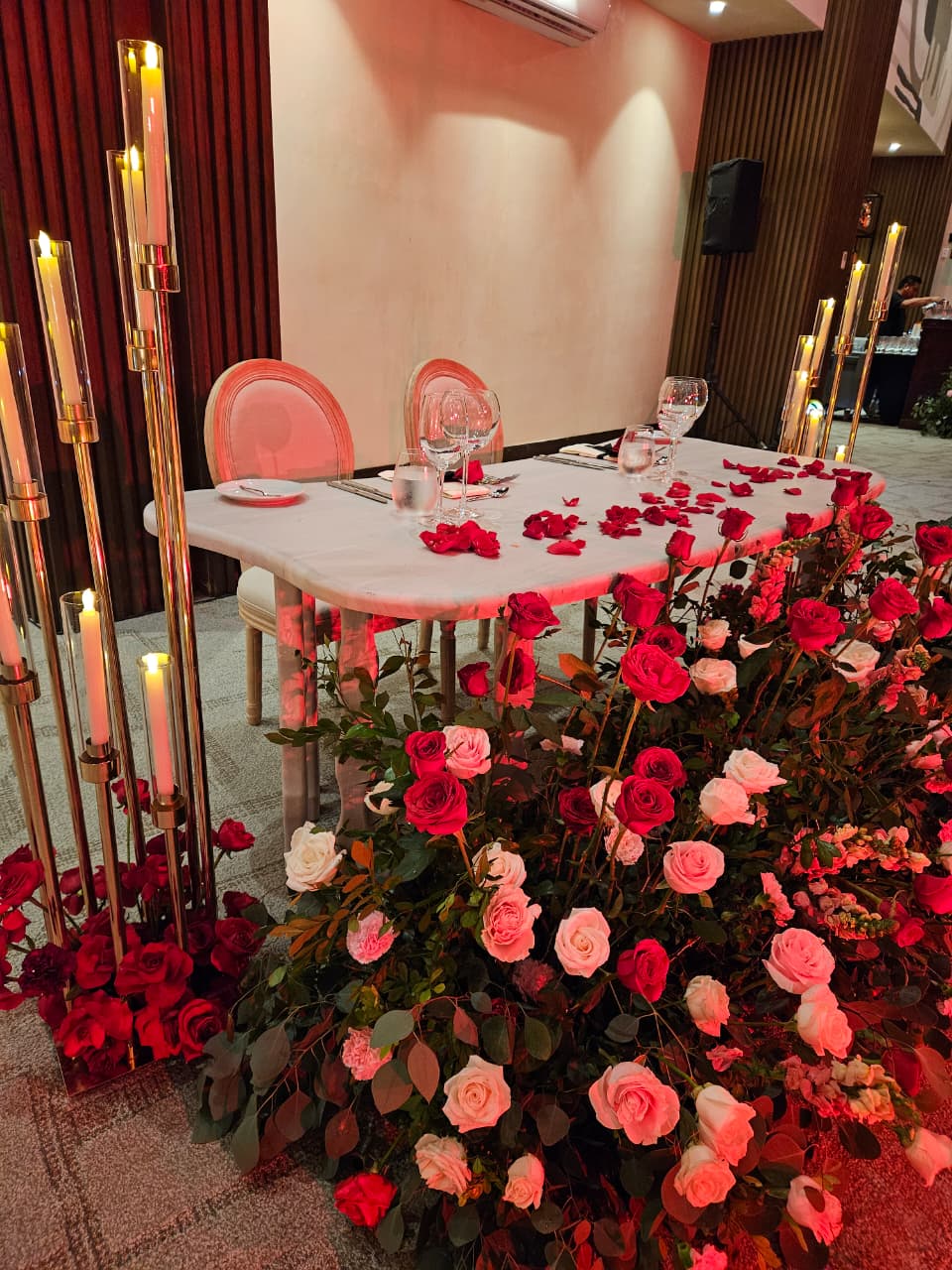 jaguar b 12 be all inclusive Romantic table setting for two with a white tablecloth, pink chairs, glassware, and rose arrangements in a decorated hall.