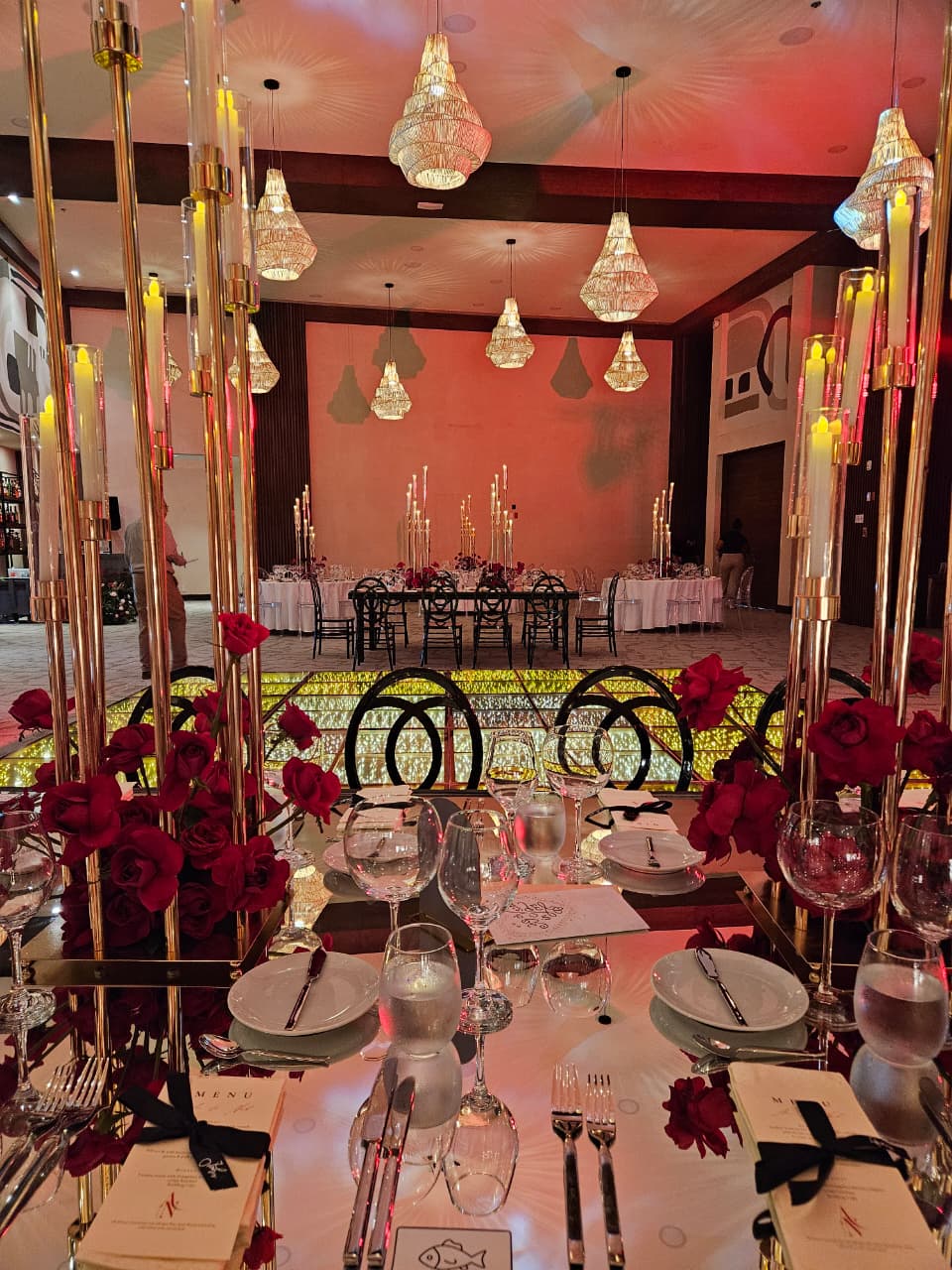 jaguar b 13 be all inclusive Elegant banquet table set for a formal event with red rose centerpieces, gold candle holders, and polished glassware in a warmly lit ballroom.