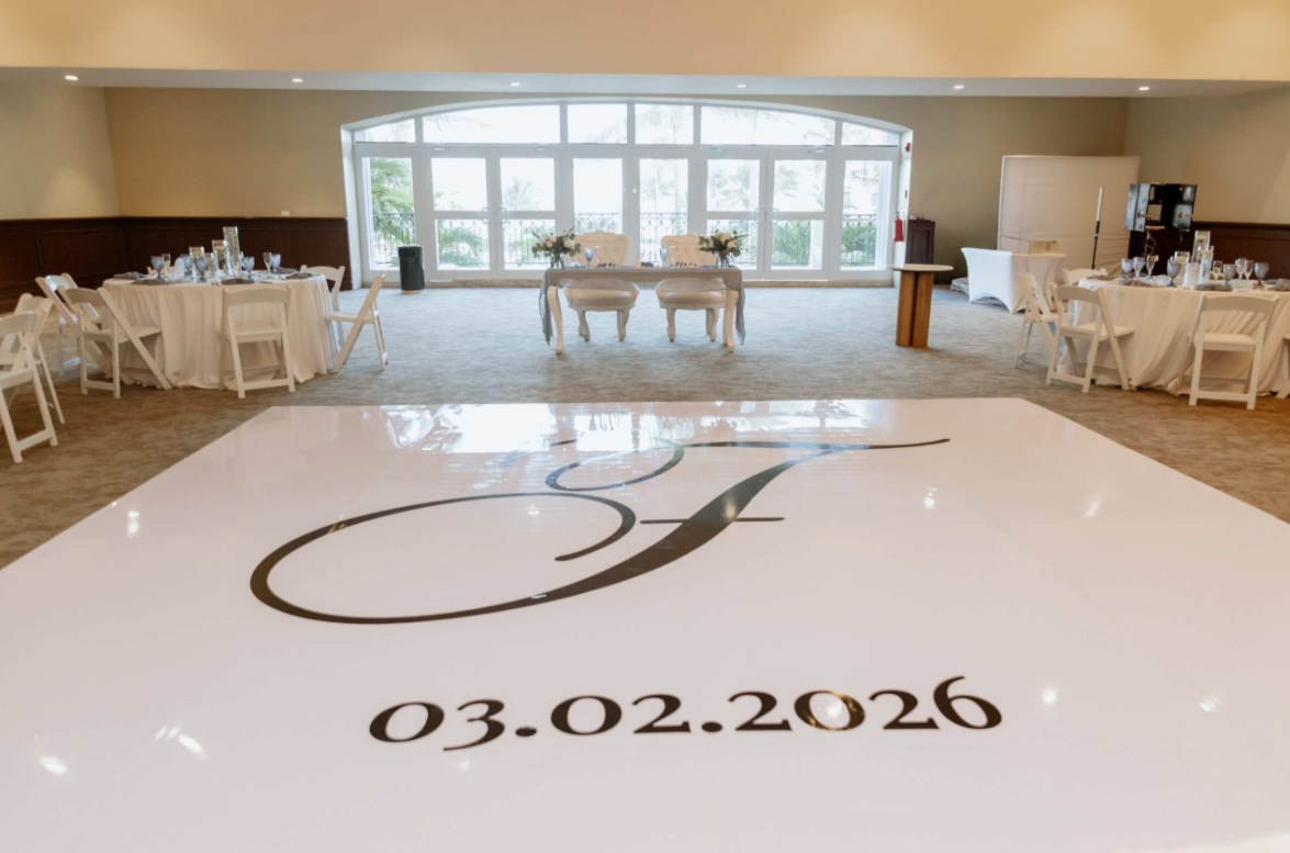 screenshot 20260616 142328 be all inclusive Bright reception hall with round tables, white chairs, and a large white dance floor decal displaying initials and the date 03.02.2026.